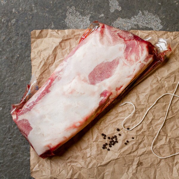 Raw Iberico pork striploin on butcher paper with peppercorns & string