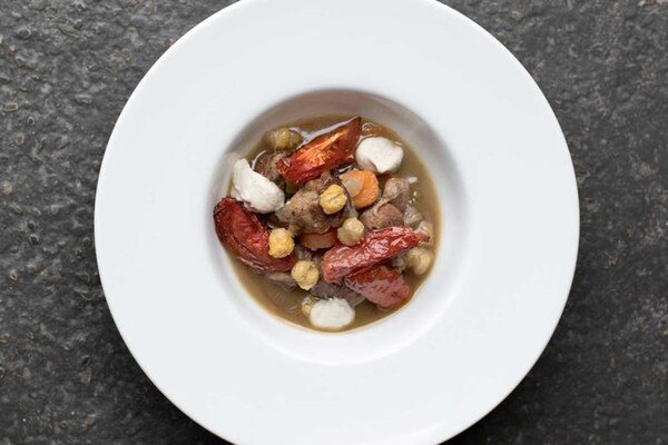 Moroccan stew with grass-fed lamb, roasted tomatoes, fried chickpeas & cashew cream in a white bowl