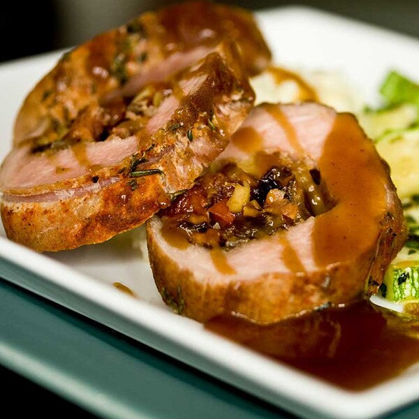 Cooked Beeler’s pure pork boneless loin, stuffed, sliced, with brown sauce on white plate